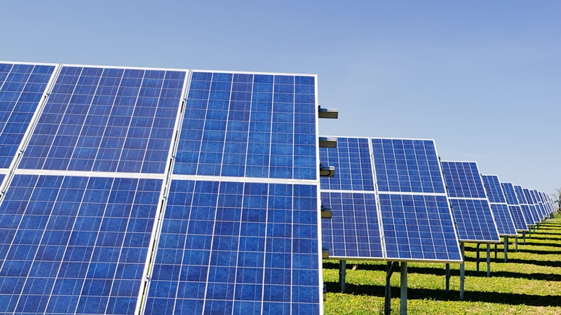 Solar panel farm on green grass with a blue sky